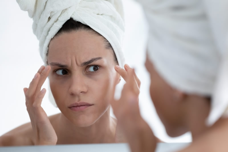 お風呂上りに鏡で自分の顔を気にしている女性