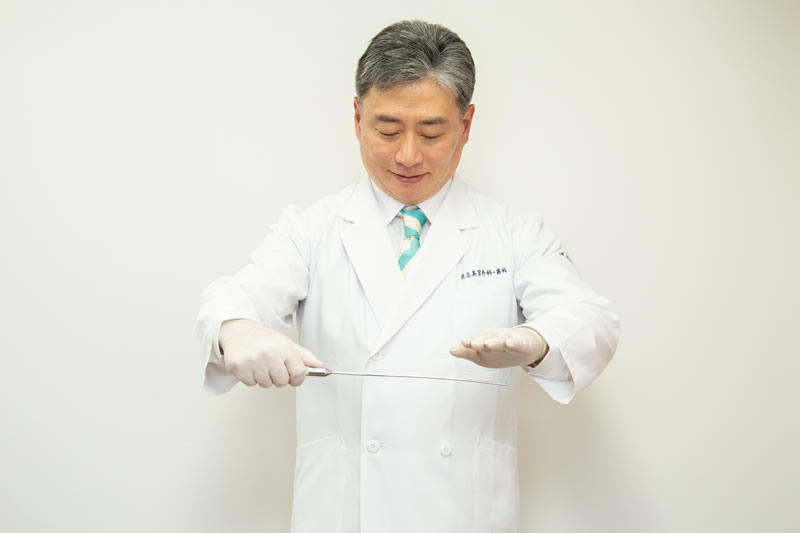 カニューレを持って脂肪吸引を説明する医師