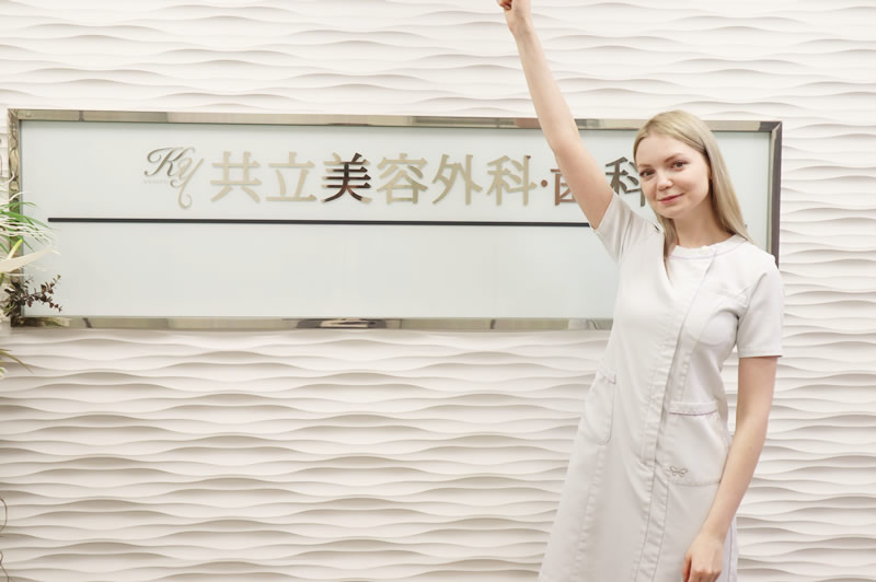 共立美容外科の前で手を挙げている女性