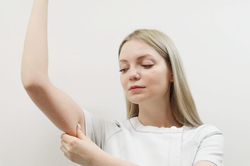 二の腕のたるみを引っ張る女性