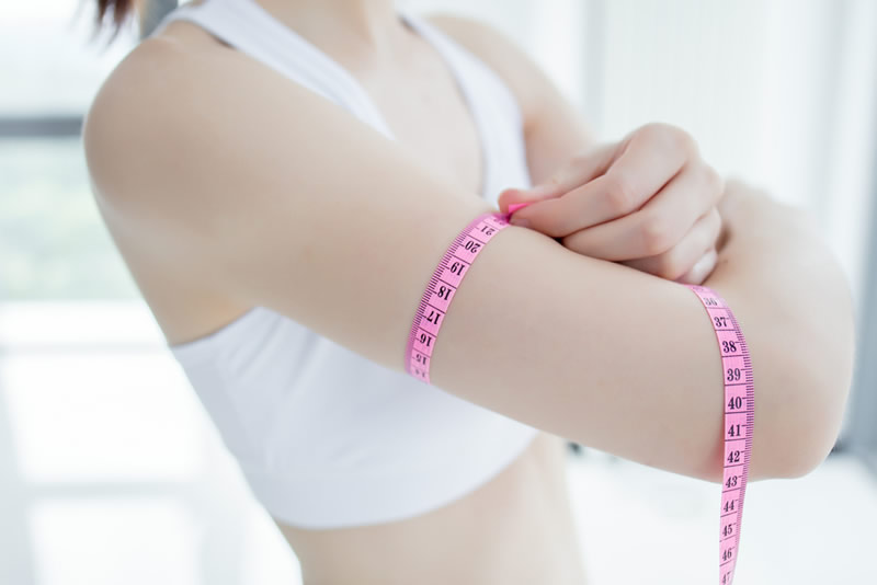 二の腕のサイズを測る女性