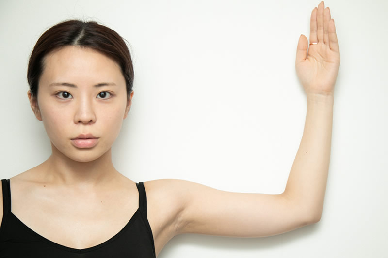 二の腕を見せる女性