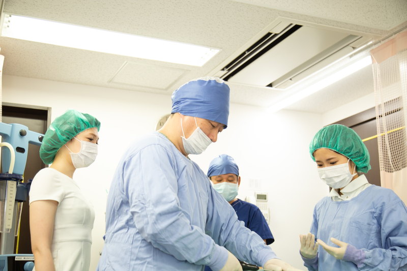 手術室で太ももの脂肪吸引の手術をする医師と看護師