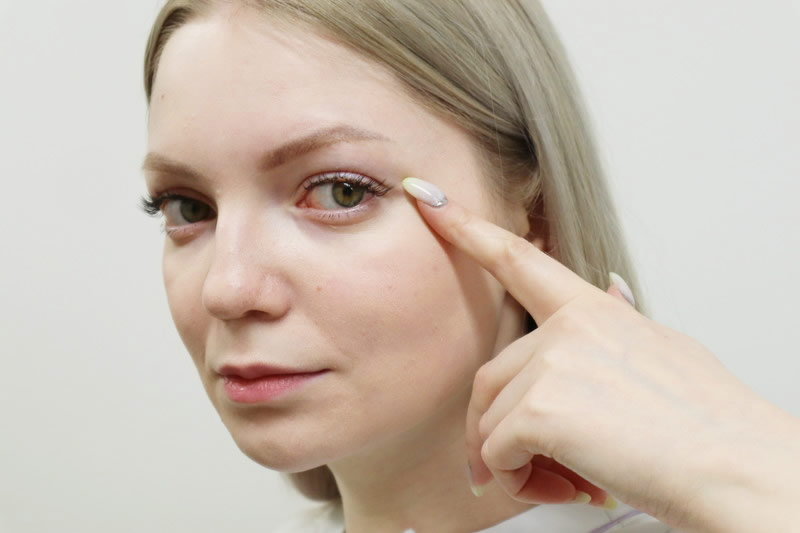 目を指さす女性