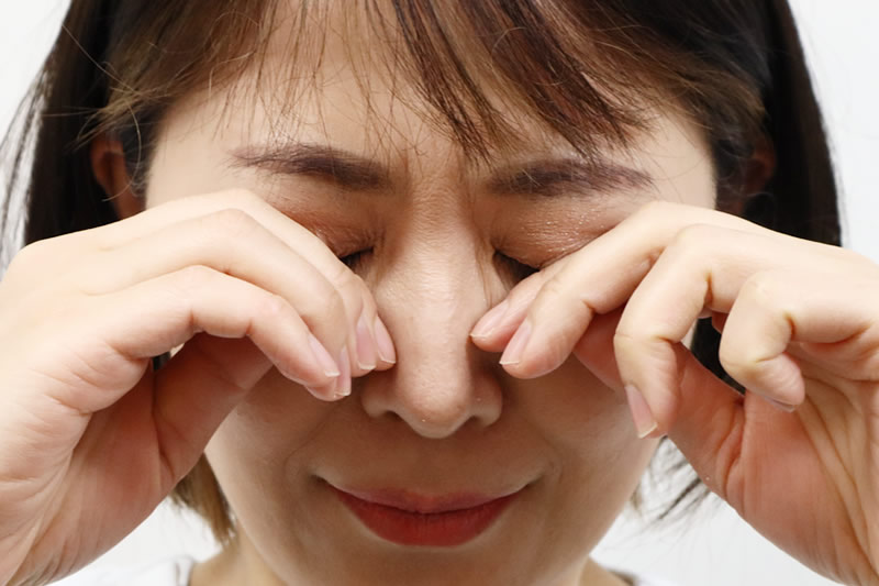 瞼が重くて目をこする女性