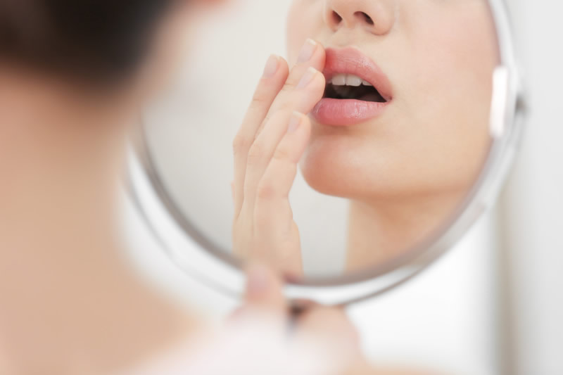 鏡で口元を確認している女性