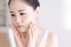 鏡の前で顔を触っている女性