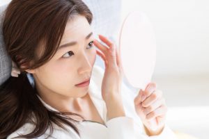鏡を見て瞼を気にする女性