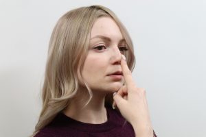鼻を指さす女性