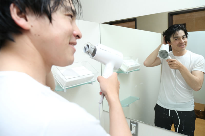 髪をドライヤーで乾かしている男性
