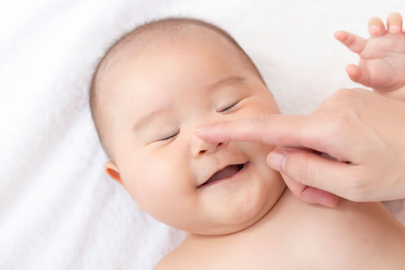赤ちゃんの鼻を触る女性