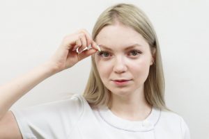 瞼をつまむ女性