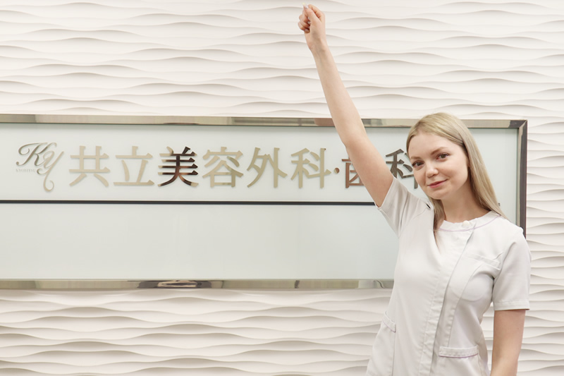 共立美容外科の前で手を挙げている女性