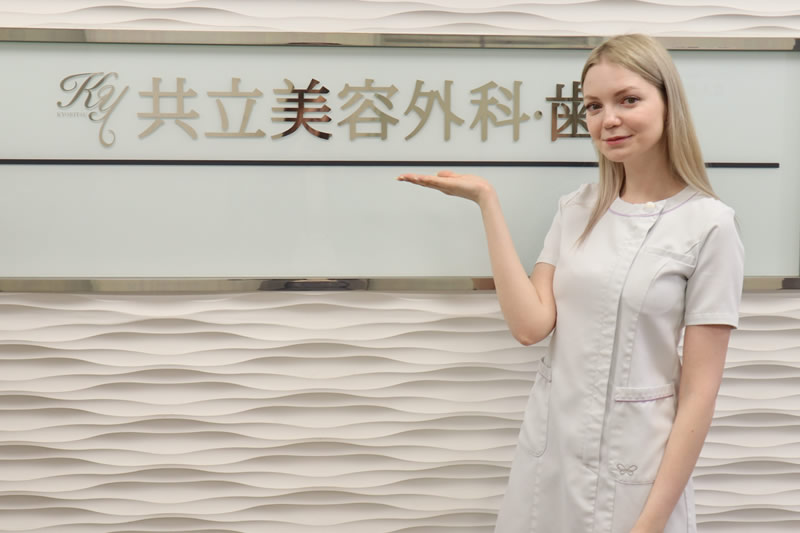 共立美容外科の看板の前に立つ女性