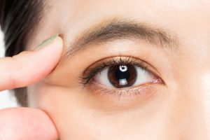 右手で目をつまんでいる女性