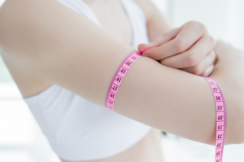 女性の二の腕を計測しているイメージ