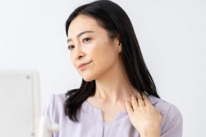 鏡で首のしわを気にしている女性のイメージ