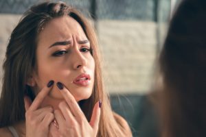 鏡の前でニキビを気にしている女性