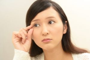 鏡の前で目元を気にしている女性