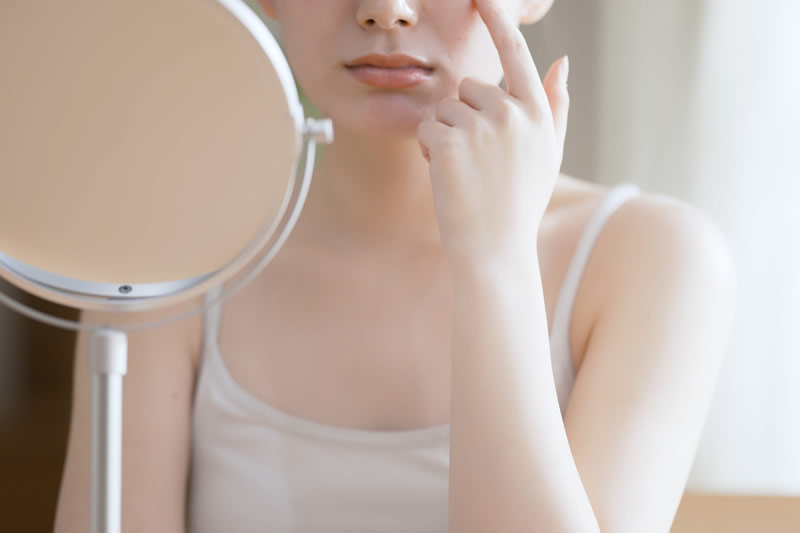 鏡を見て肌を気にしている女性