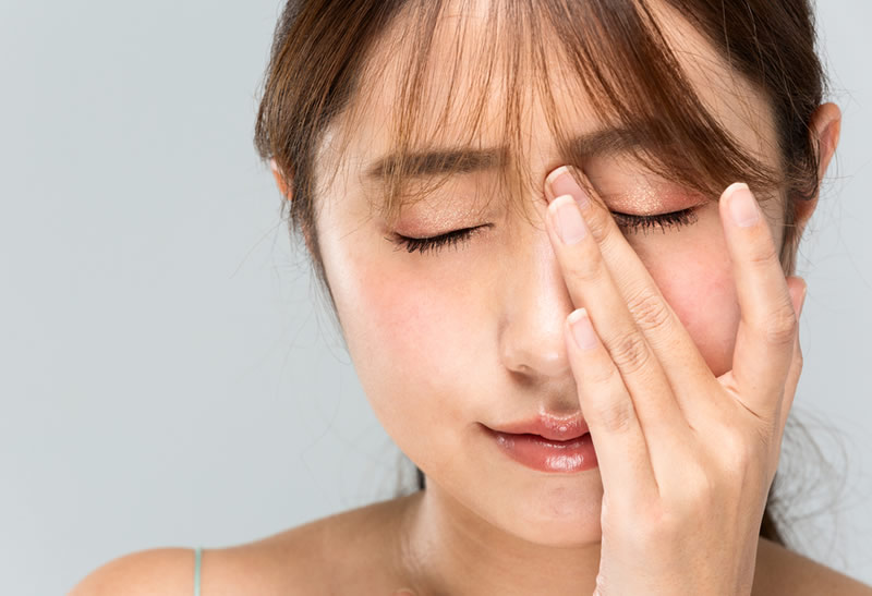 顔を触って辛そうにしている女性