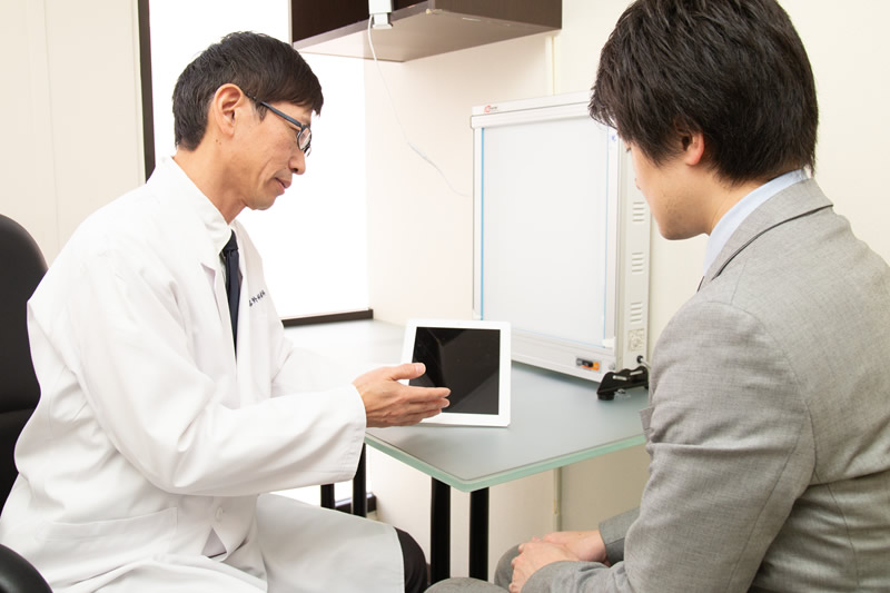 鼻のプロテーゼの相談を医師にする男性の患者