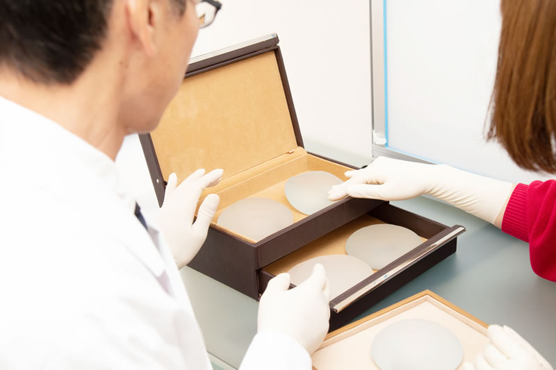 いろいろな豊胸バックを説明している医師と聞く患者