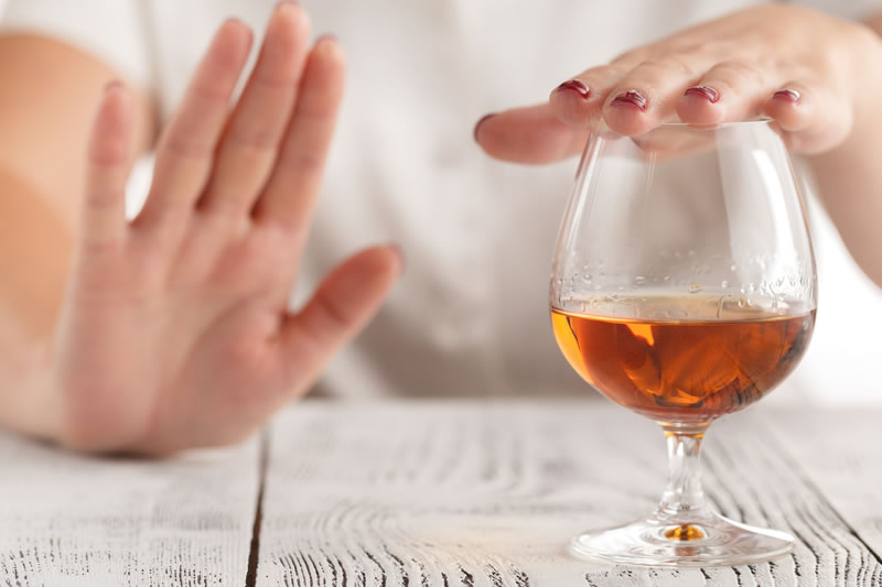 差し出されたお酒のグラスを手で断る様子。術後に飲酒を控えるイメージ
