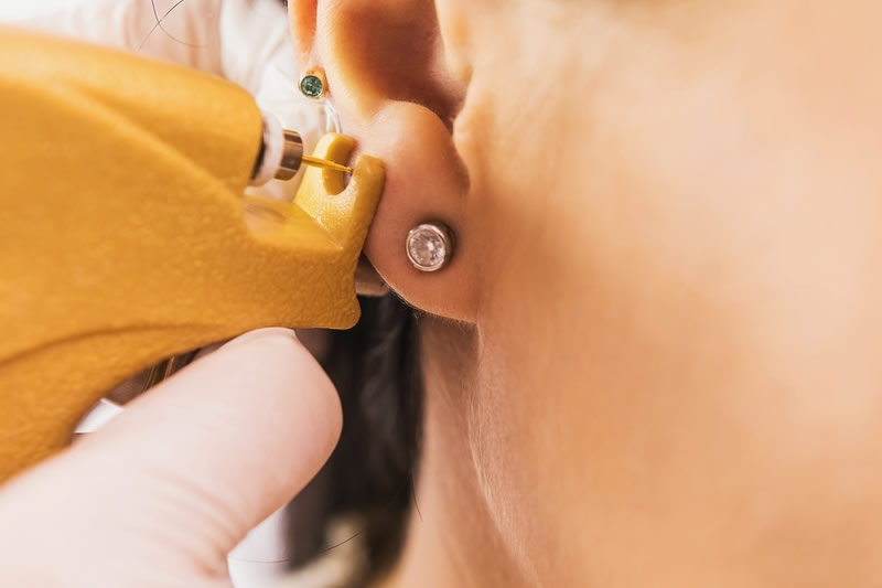 ピアッサーで耳に穴を開けているところ