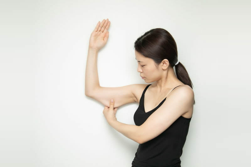 二の腕のたるみを確認する女性