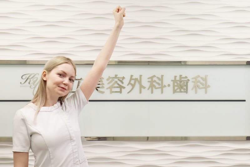 共立美容外科の看板の前で手をあげる看護師