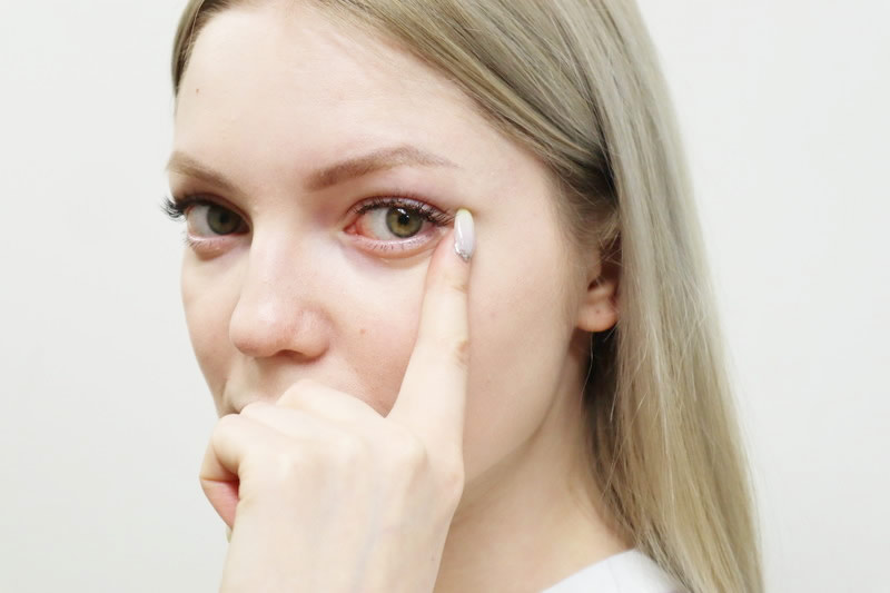 目を指さす女性