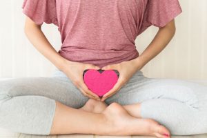 股にハートの模型を置く女性