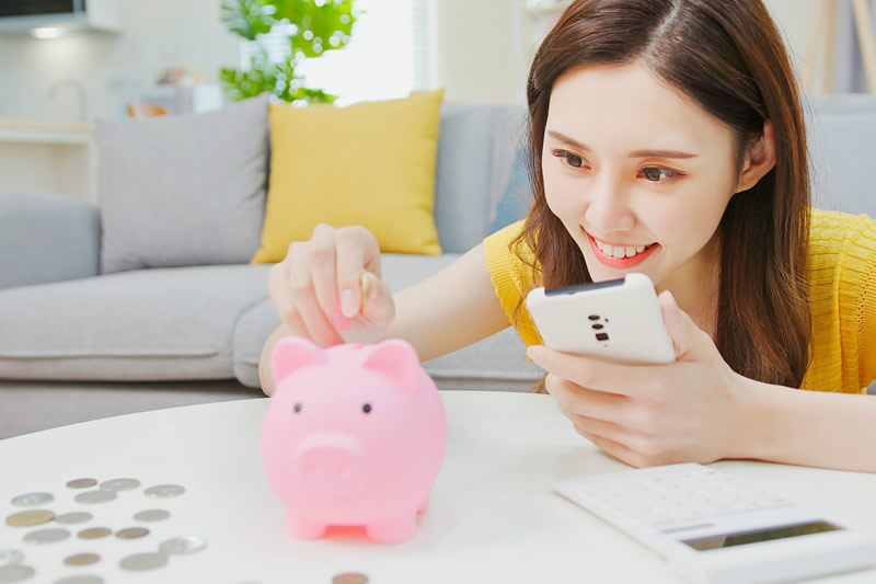 貯金箱にお金を入れている女性