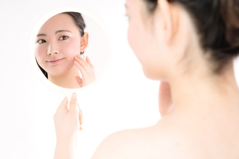 鏡でニキビをチェックする女性