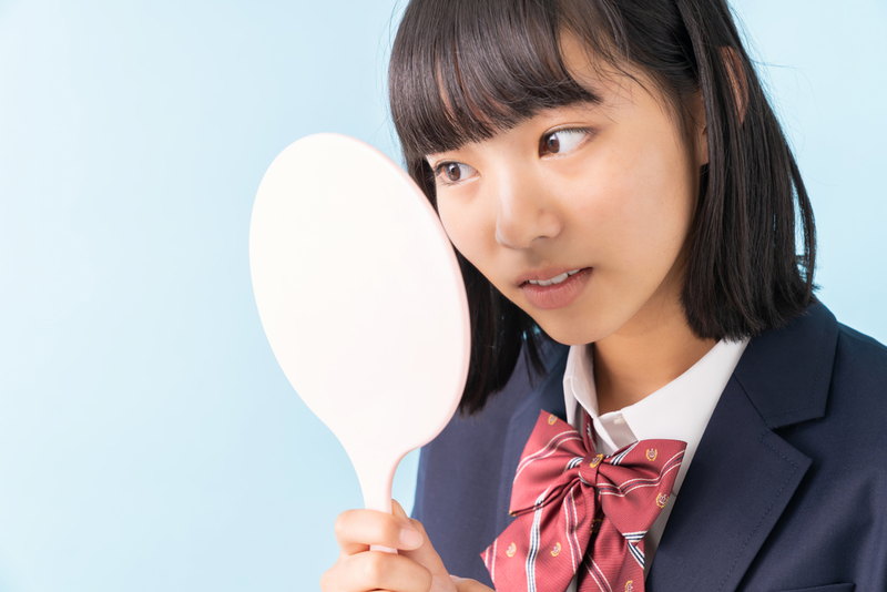 鏡で肌質を確認する女子高生