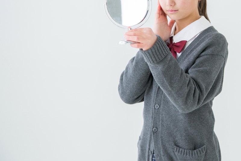 鏡を見て毛穴を気にする女子高生