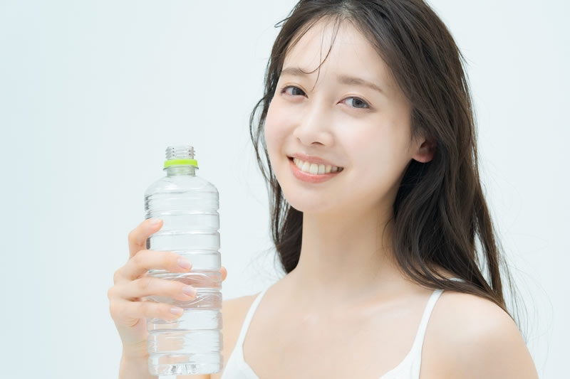 ペットボトルを手に取る女性