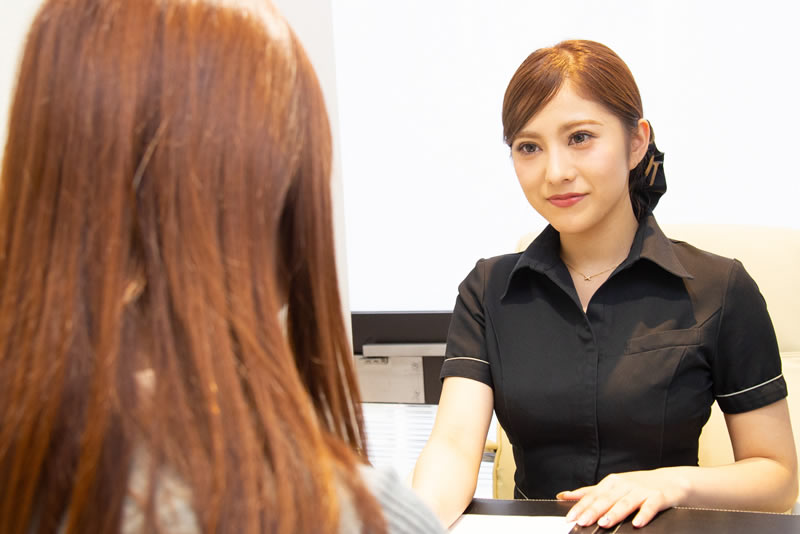 Oラインの脱毛の料金を説明するスタッフ