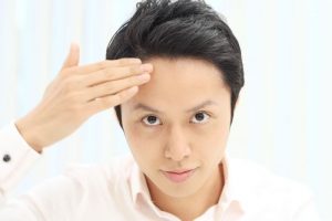 鏡で頭皮鏡で頭皮をチェックする男性をチェックする男性