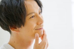 顎髭の剃り残しを手で触る男性