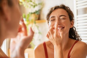 鼻の黒ずみを鏡で確認する女性