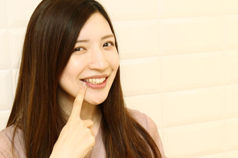 歯を指さす女性