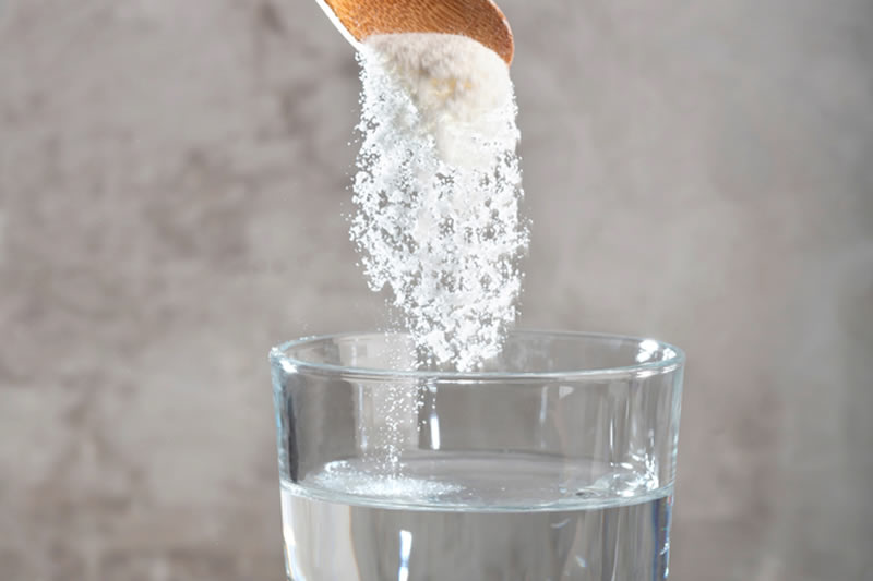 コラーゲンの粉末をコップの水に入れているところ