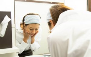 鏡で頬に触れている女性