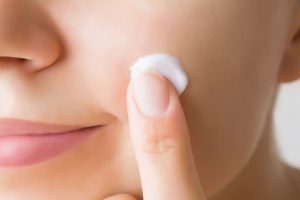 フェイスラインにできたニキビケアをしている女性