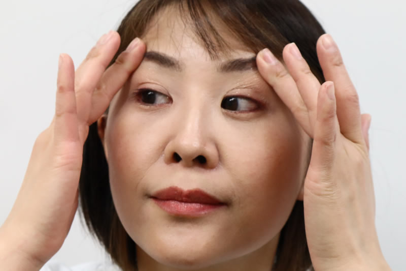 瞼をマッサージしている女性