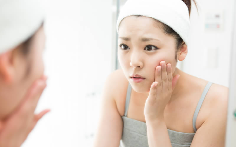 肌の乾燥やシワが気になって鏡を見ている女性