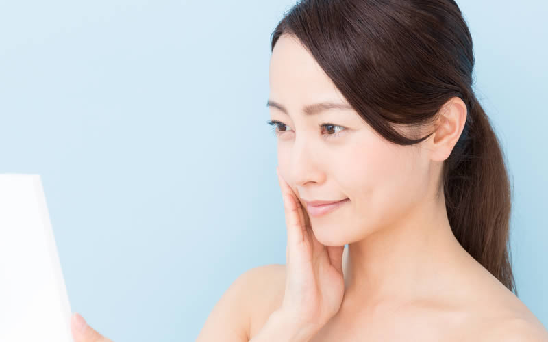 鏡で目元を見ている女性