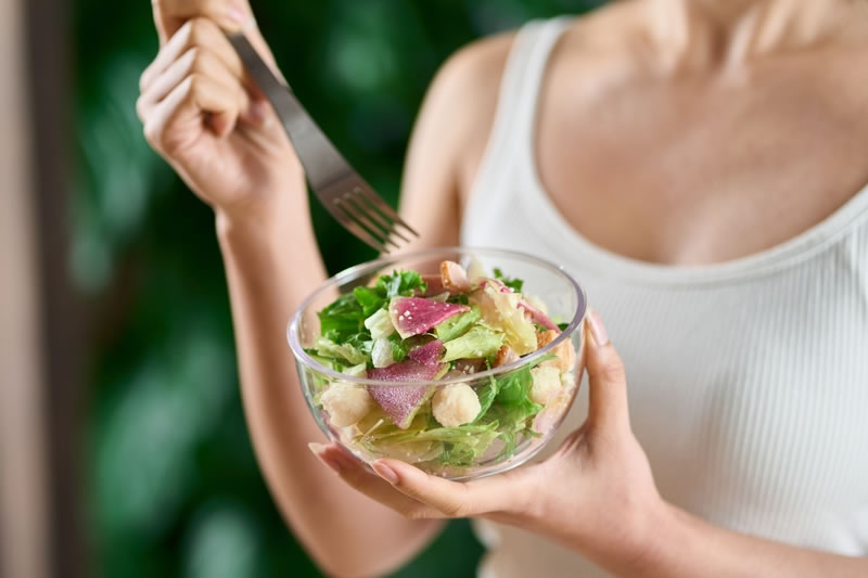 よくかんで食べるために歯ごたえのあるサラダを食べている女性